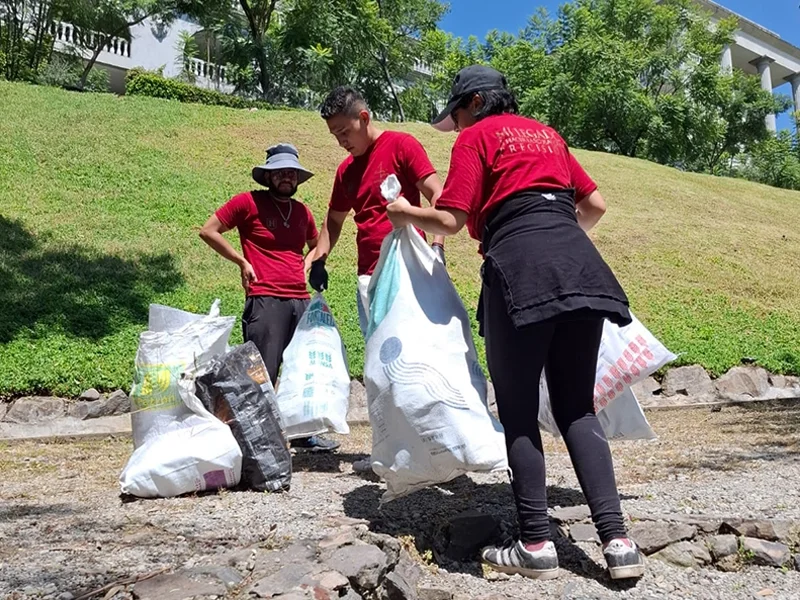 Tres jóvenes limpiando, parte del programa de responsabilidad social Humanitas